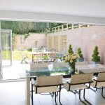 Internal view of aluminium bi-fold doors London from dining room with table looking out into garden